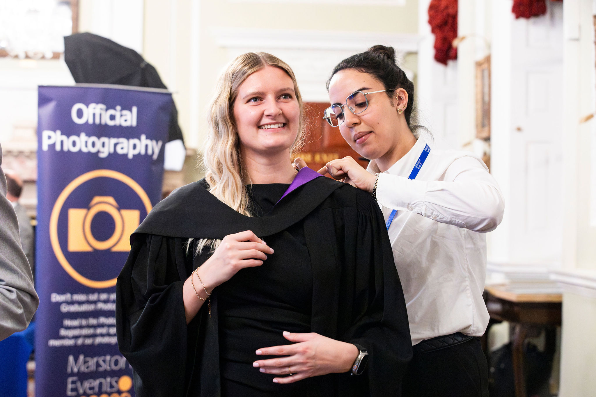 Image of graduate being fitted with gown