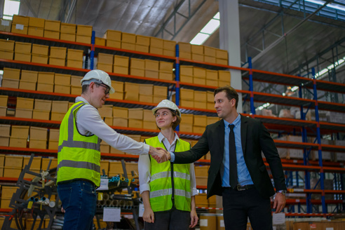 Two people having a handshake in a warehouse.