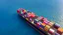Freight liner crossing the ocean, carrying dozens of multi-coloured containers