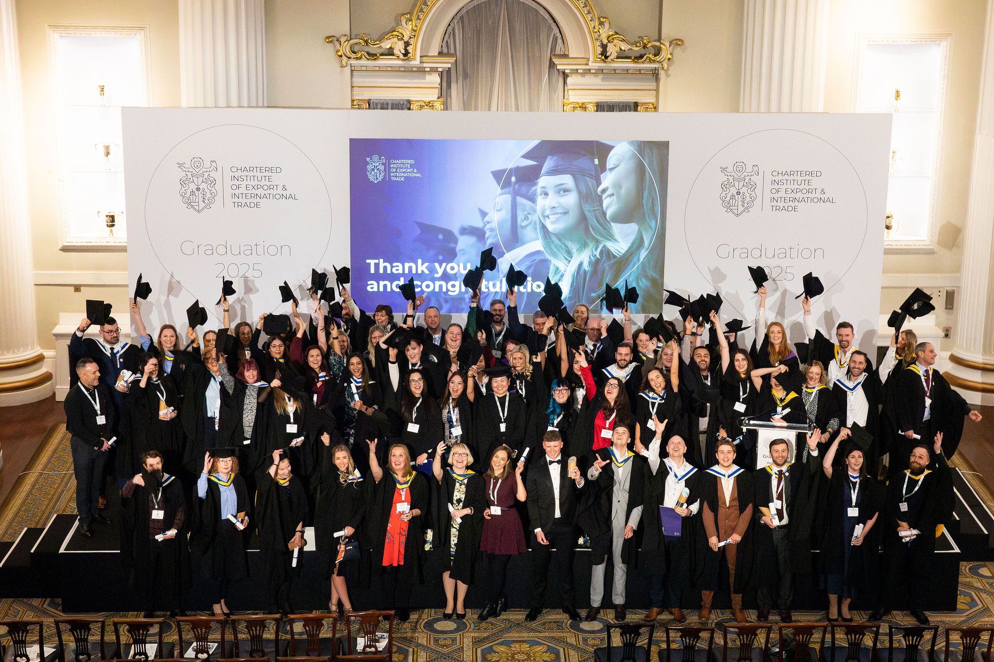 Image of graduation with large group of gowned individuals throwing hats in the air